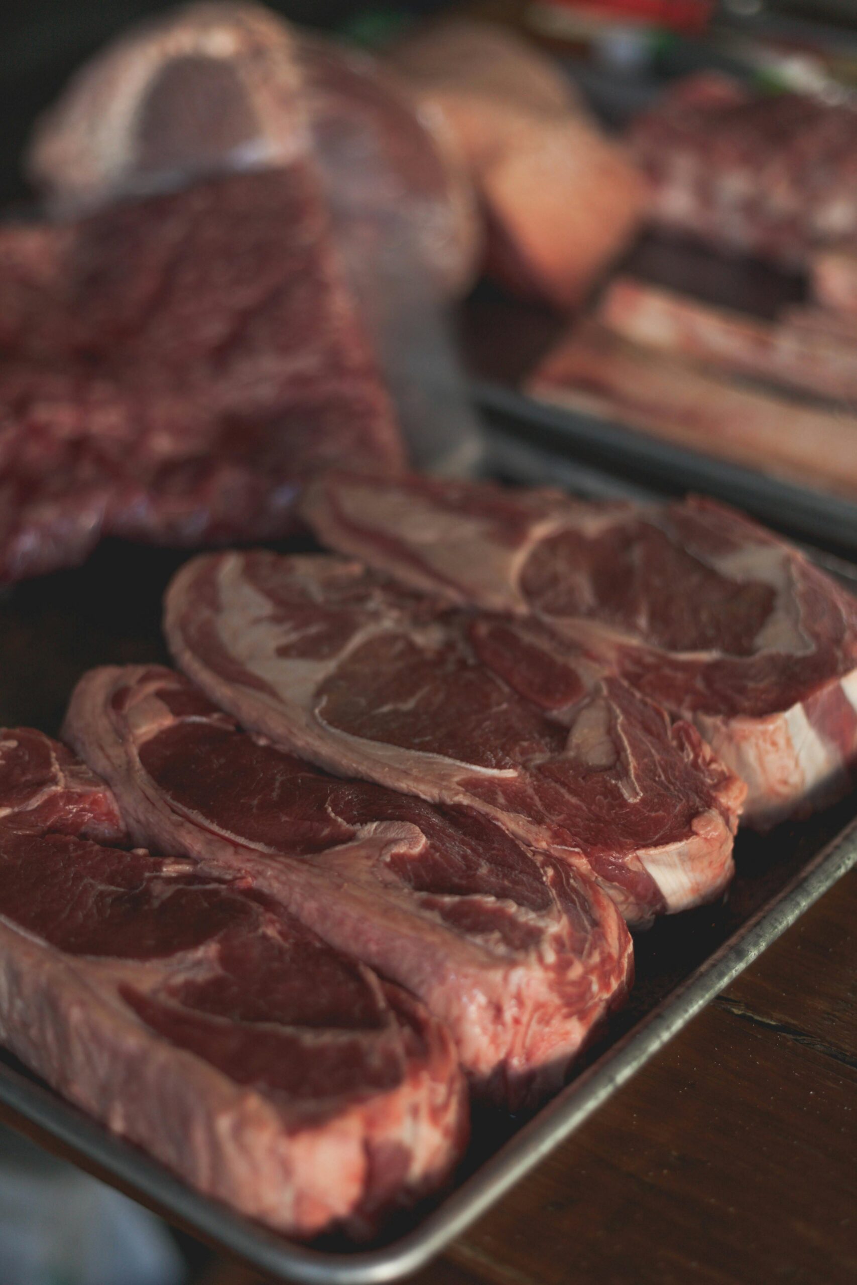 Fresh raw beef cuts on a tray, perfect for cooking enthusiasts and food markets.